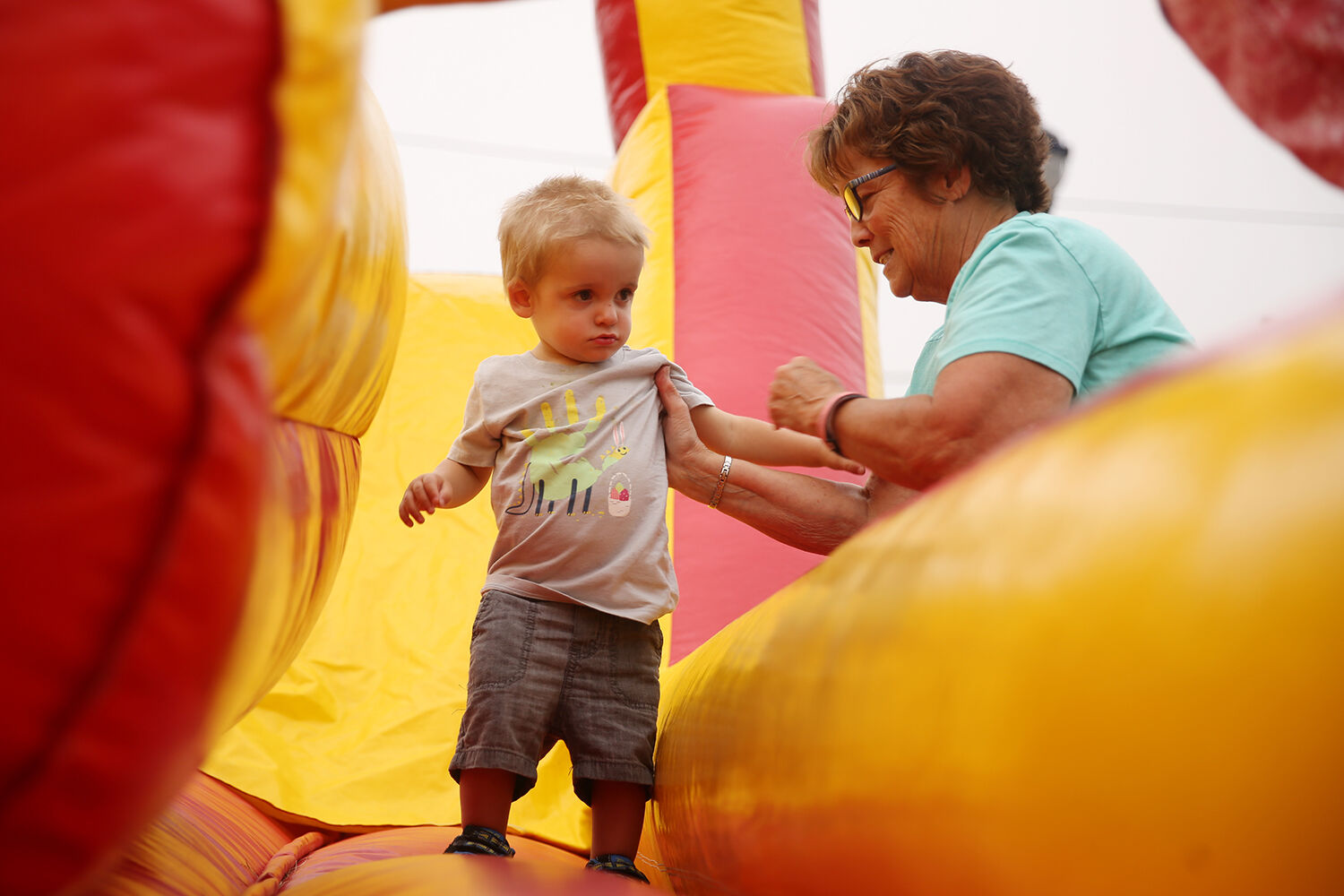 Nikki Lohse helps to balance friend Geis, 1, on the bouncy house